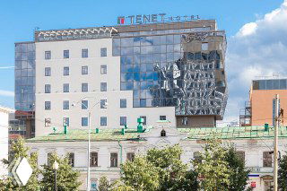 Современный фасад отеля с зеркальными поверхностями и логотипом на крыше на фоне неба — вариант размещения для участников конференции по фитнесу в Екатеринбурге