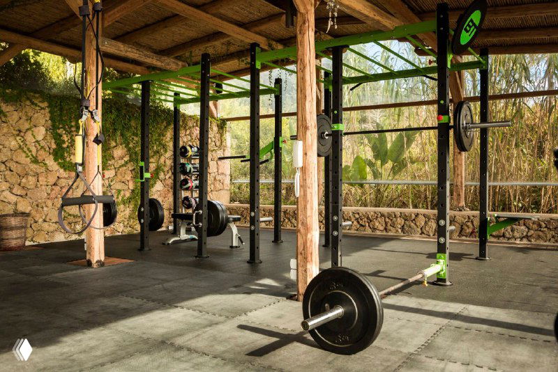 Функциональная тренировка на открытой площадке: штанга и элементы кроссфита в инфраструктуре отеля, оборудование размещено под крышей.