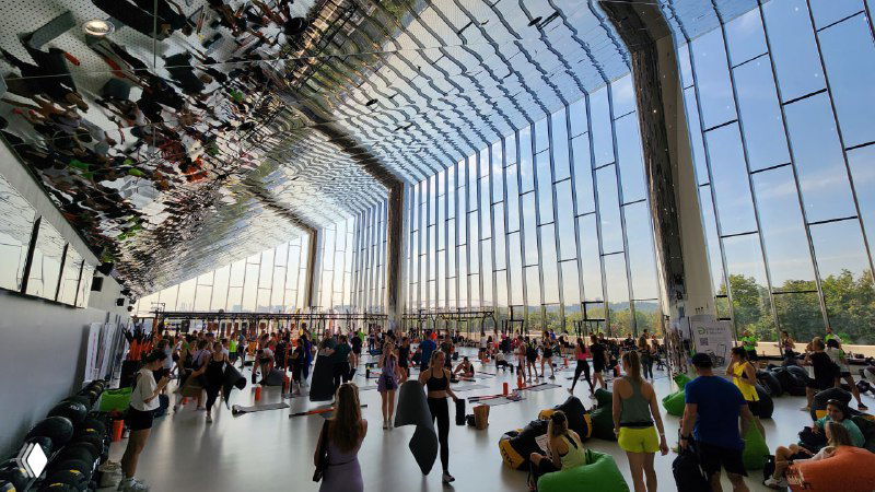 Просторное фойе с потоком людей и группами обсуждающих коллег — кадр показывает плотный трафик на деловой программе мероприятия.