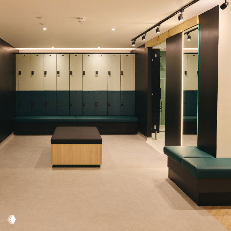 Раздевалка ForestHouse: ряд шкафчиков, скамьи и зеркала в минималистичном стиле, приглушённое тёплое освещение и аккуратная отделка интерьера клуба.