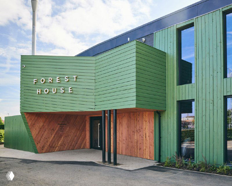 Фасад ForestHouse: зелёная деревянная отделка и вывеска на входе, архитектура небольшого клуба здоровья с акцентом на природные материалы и уютную атмосферу.