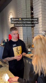 Сотрудник в чёрной футболке беседует с посетительницей у стойки в уютном велнес‑пространстве — сценка как идея для развлекательного рилса и вовлечения аудитории.