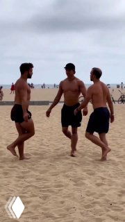 Трое мужчин на пляже в шортах идут и разговаривают; кадр уличного рилса с простым действием, подходящим для вирусного охвата в аккаунте велнес‑бренда.