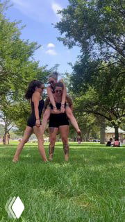 Три человека в парке выполняют трюк с человеком на плечах — простой смешной сюжет для рилса, который призван вызывать улыбку и репосты аудитории.