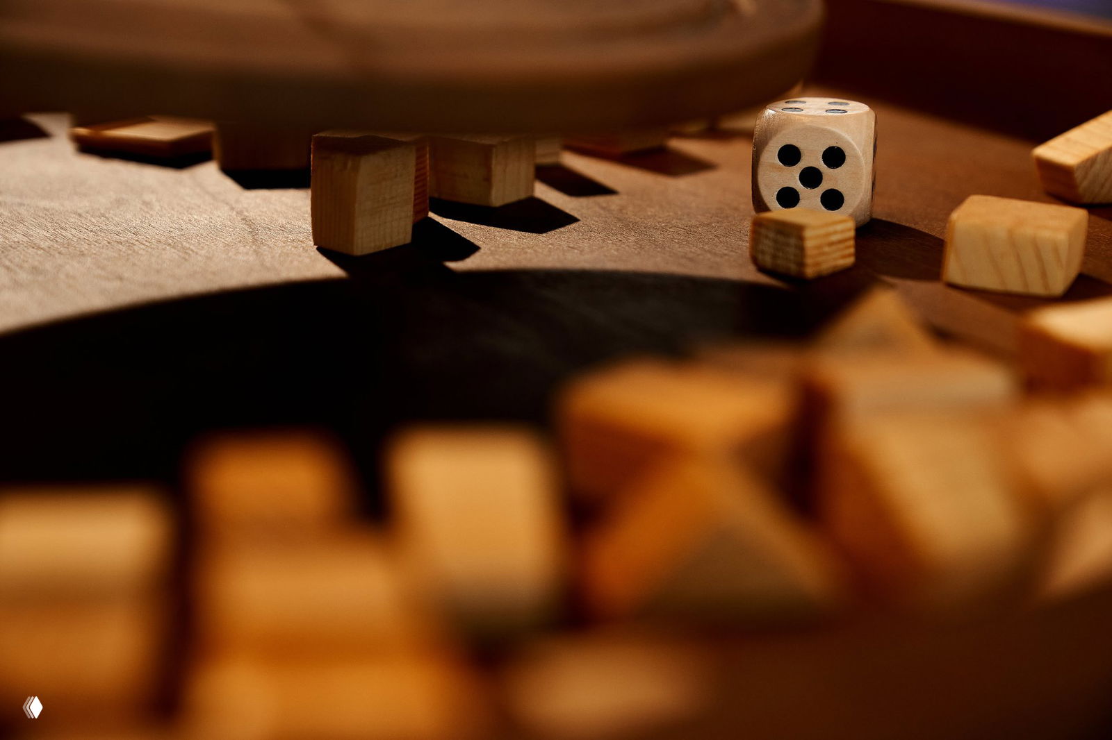 Макросъёмка деревянных фишек и кубиков, рядом деревянный игральный кубик с точками, тёплое освещение и акцент на фактуру дерева.