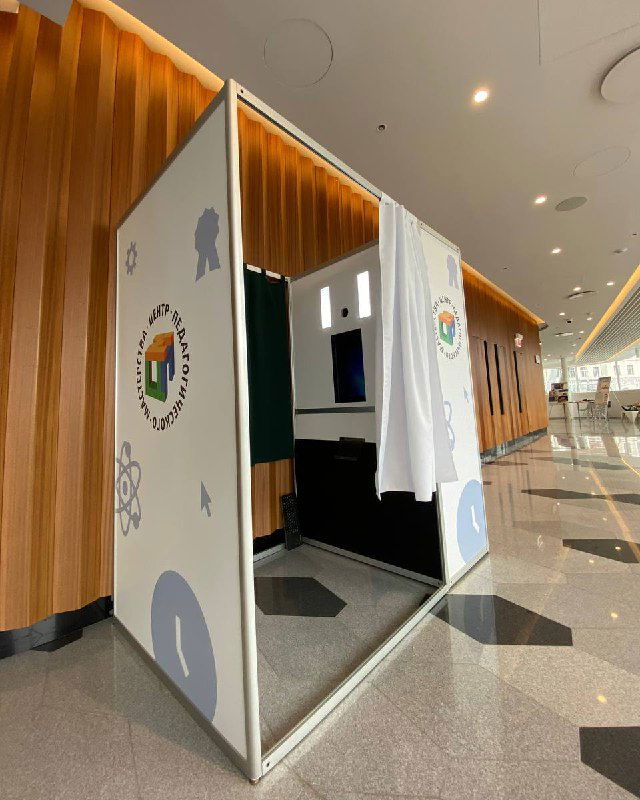 Фотокабина в виде брендированной кабинки, установленная в фойе: закрытая конструкция с фирменной графикой для индивидуальных фотосессий гостей мероприятия.