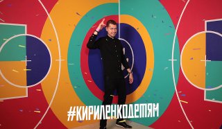 Человек стоит на яркой 3D‑фотозоне с круговыми цветными узорами — пример оформления фотозоны для мероприятий и промо‑съёмок.