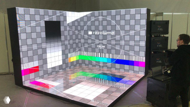 Угловой светодиодный пол и экран с тестовой цветовой шкалой: проверка отображения и настройка изображения, рядом оператор у пульта.