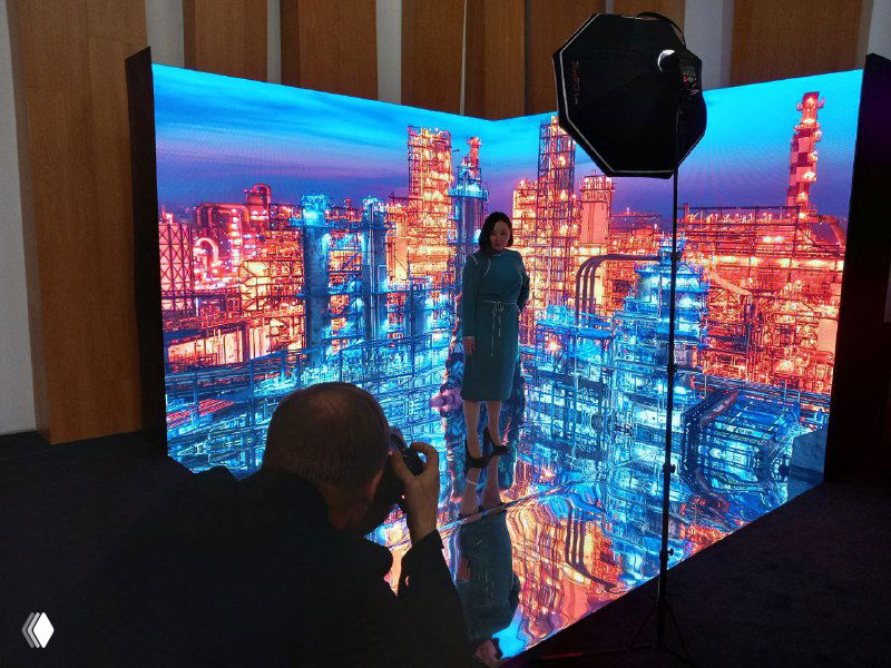 Выездная фотостудия в действии: фотограф снимает модель на фоне яркой LED‑панели и студийного света, демонстрация съемочной зоны на мероприятии