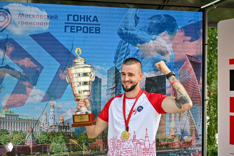 Участник держит большой кубок на фоне яркого светодиодного экрана с городским баннером — пример использования арендуемого экрана на мероприятии.