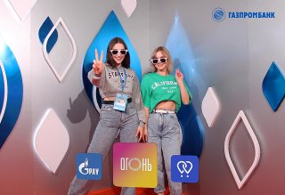 Две молодые женщины позируют перед Bullet Time 3D фотозоной на VK Fest 2023: плакаты, логотипы и реквизит в кадре.