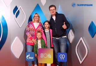 Семья с детьми улыбается перед фотозоной Bullet Time 3D на VK Fest 2023: брендированные таблички и фон с логотипом.