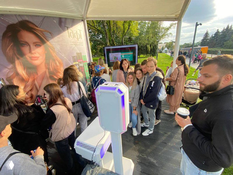 Фотостойка MixAp на городском событии: белая стойка с подсветкой, группа гостей в очереди у павильона, виден баннер.
