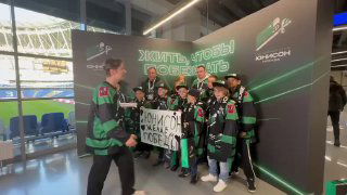 Группа людей в хоккейных форме на фоне брендированной фотозоны MosFotobudka; участники позируют с плакатом во время мероприятия.