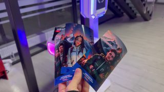 Руки держат печатные фотополоски с портретами гостей; на заднем плане видна часть студии и световая инсталляция фотозоны — пример результата фотостойки