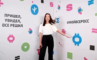 Женщина позирует в интерактивной фотозоне MosФотобудка на фоне яркой брендовой стены с цветной графикой, символами и слоганом