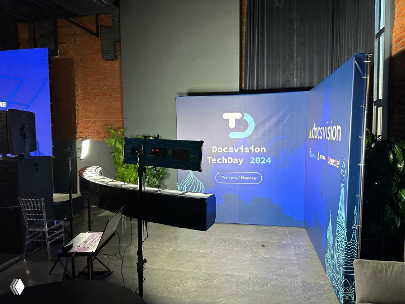 Сцена с бренд‑фоновой стеной TechDay и изогнутой 3D‑фотозоной Bullet‑Time; видны камеры, свет и монтажная техника на площадке.