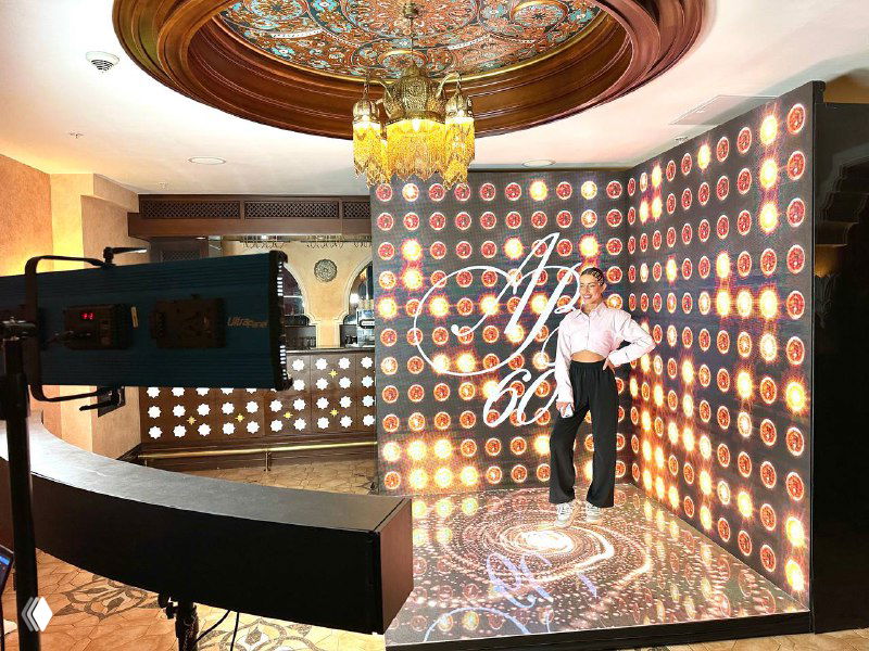 Интерактивная 3D‑фотозона с крупным LED‑экраном и подсветкой; человек позирует на подиуме рядом с буллет‑тайм ригом.