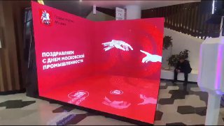 Кривой красный LED‑экран в фойе с графическими элементами и текстом поздравления; пример LED‑фотозоны для мероприятий.
