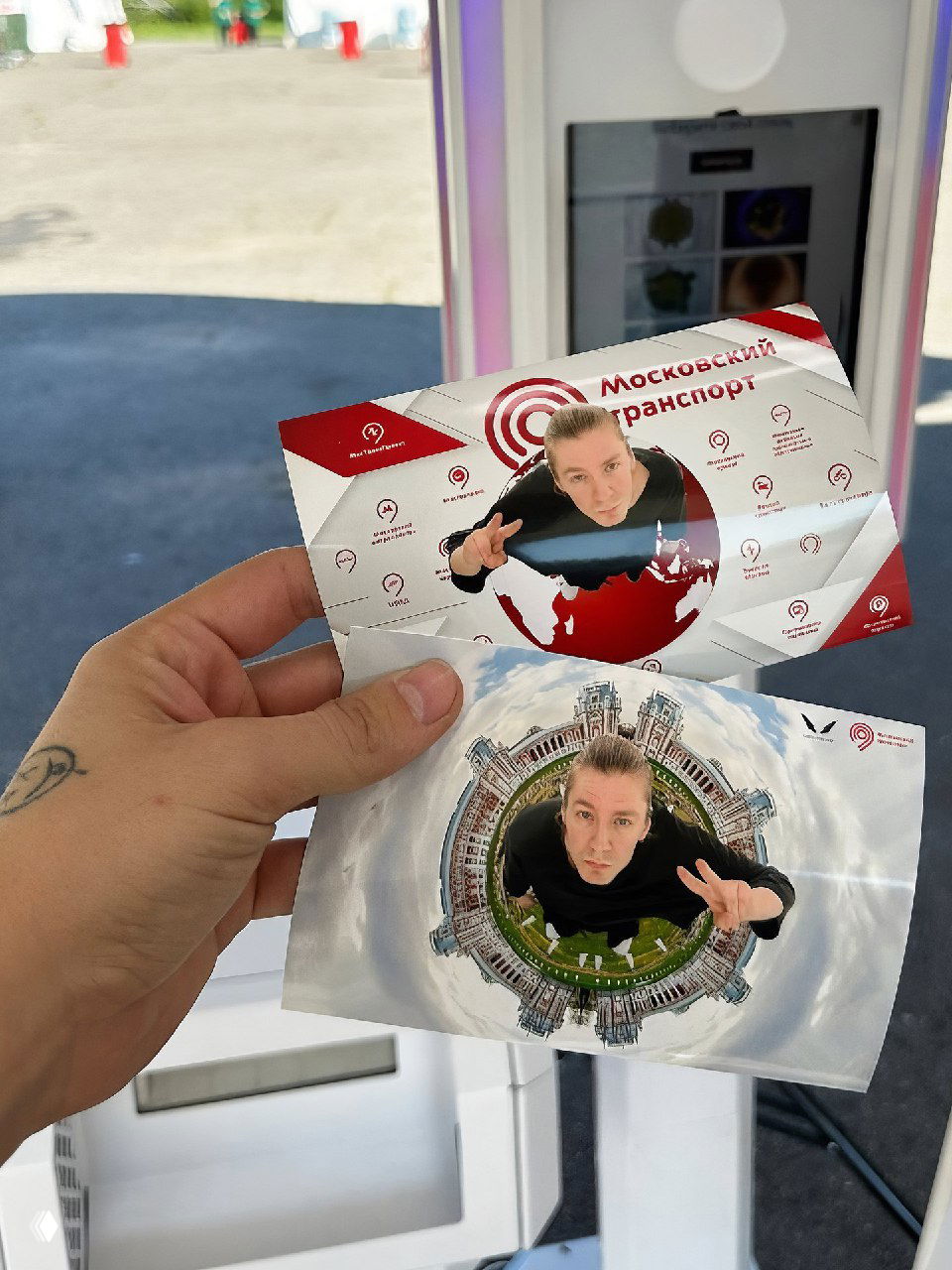 Рука держит две распечатки: брендированная карточка и фото с эффектом «маленькой планеты», крупный план на печатные сувениры с фотозоны.