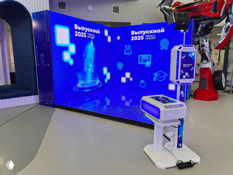 Большой изогнутый LED‑экран в выставочном зале с напольным и задним подсветом, перед экраном — белая фотостойка для печати снимков и GIF