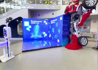 Изогнутый светодиодный LED‑экран на полу и сзади в выставочном пространстве рядом с фотостойкой; демонстрация фотозоны для мероприятий и брендинга гостей