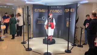 Фотозона Spinner 360: участник на вращающейся платформе, вокруг вертикальные световые столбы, зрители и брендовый стенд.