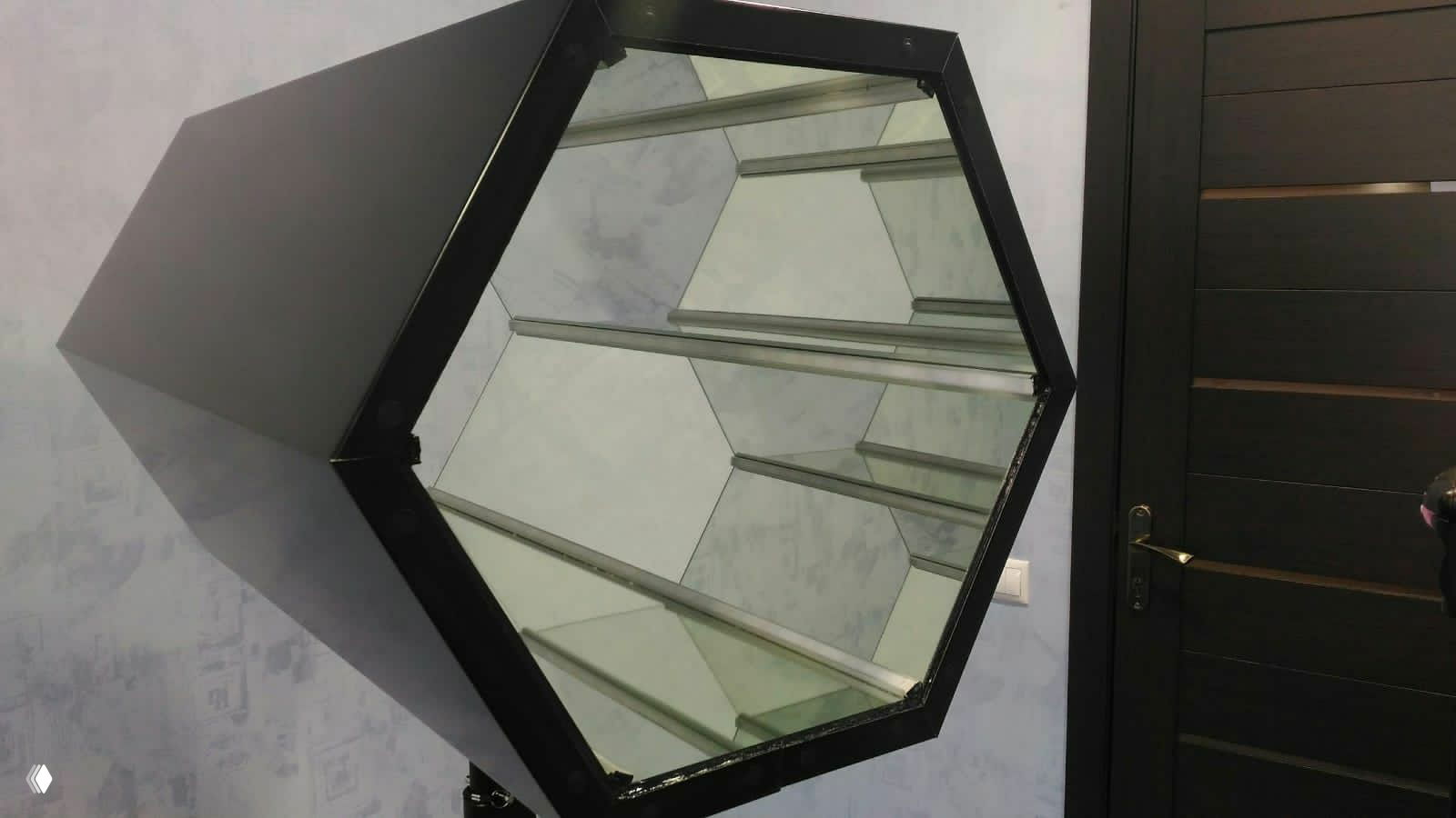 Пустая шестиугольная конструкция калейдоскопа: внутренние зеркальные панели и металлическая рама устройства, вид сбоку на установку фотостойки.