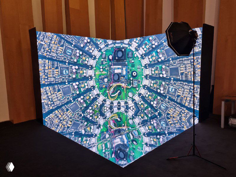 Угловая LED‑панель с яркой симметричной синей графикой, установленная как фоновая конструкция для выездной фотостудии рядом со софитами.