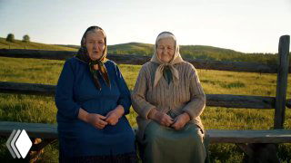 Две пожилые женщины в платках сидят на скамейке у забора в сельской местности, беседа о здоровье и «капельницах» как теме для разговоров.