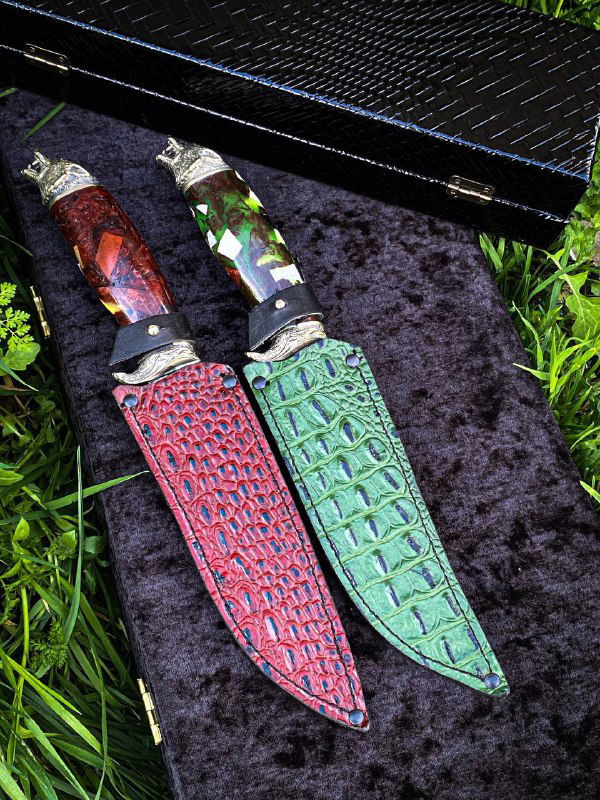 Крупный план двух ножен и рукоятей: яркие кожаные ножны и рукояти из дерева на текстильной подложке в уличной обстановке.