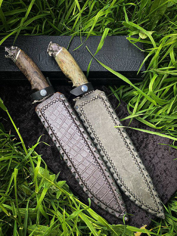Два ножа в ножнах: кожаные ножны с ручной отделкой и декоративной прострочкой, видны рукояти из карельской березы.