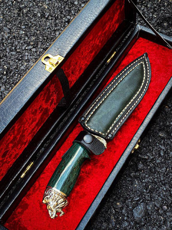 Крупный план ножен и рукояти ножа «Лев»: тёмно-зелёная рукоять карельской берёзы, прошитые кожаные ножны и элементы декора.