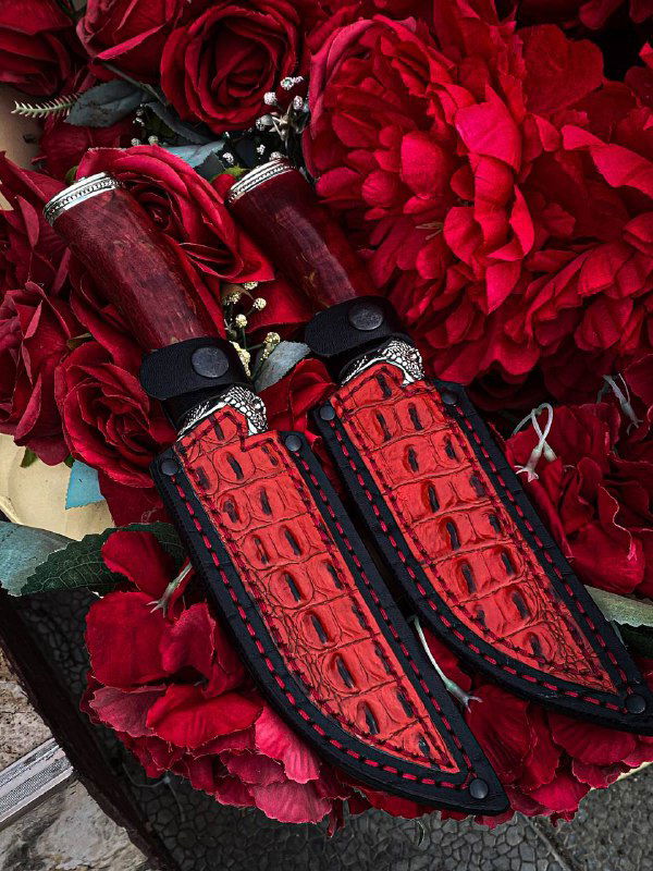 Крупный план красных кожаных ножен с чёрной отстрочкой и рукоятей из карельской березы — детали отделки и прошивки