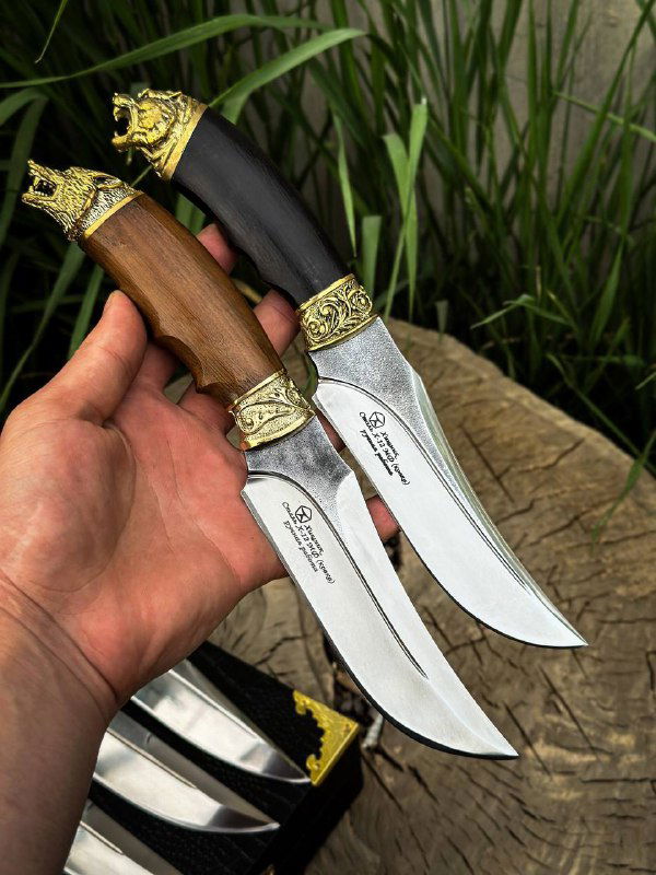 Крупный план двух ножей в руке: видны кованые клинки х12мф, тиснёные латунные гарды и деревянные рукояти разного тона.