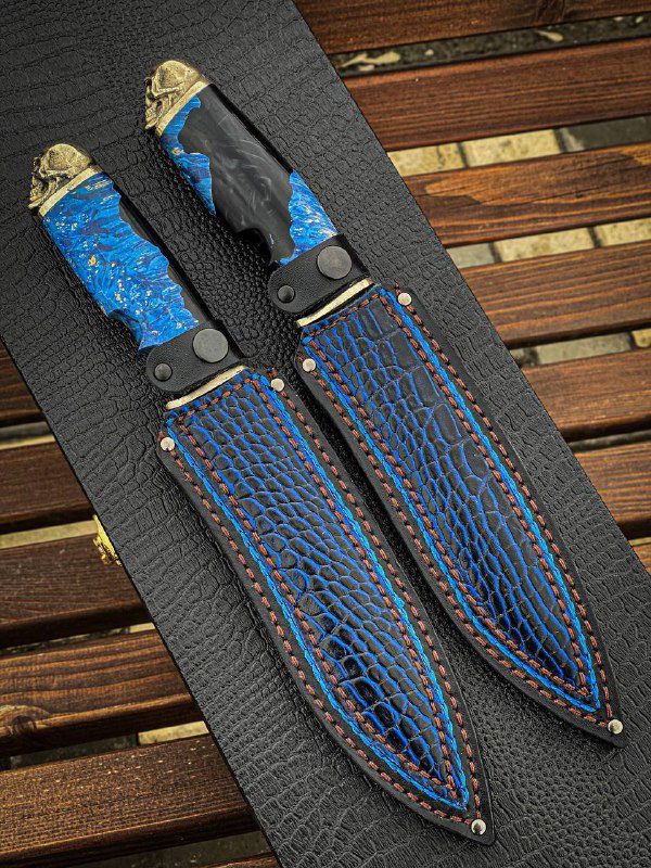 Два ножа «Череп» в комплекте с кожаными ножнами: ножны коричневого оттенка с синей прострочкой, рядом видны детали крепления.