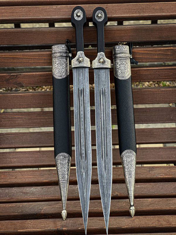 Два одинаковых кинжала в ножнах и дополнительный центральный клинок, демонстрация симметричного оформления и текстуры кожи на ножнах