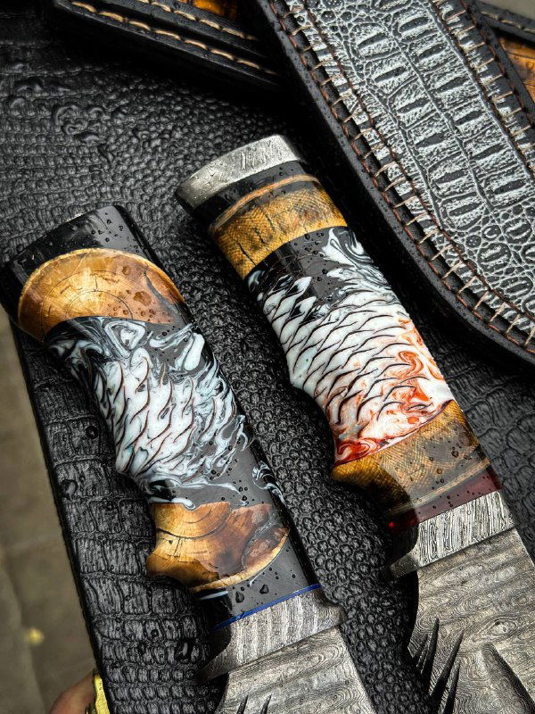 Крупный план рукоятей двух ножей с яркой отделкой: древесные вставки, металлические обоймы и декоративные элементы литья, ножны видны по краю кадра.