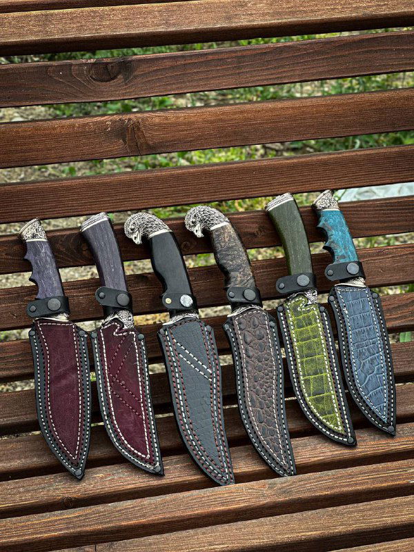 Ряд ножен и рукоятей пяти изделий, разложенных на скамье: демонстрация вариантов отделки ножен и цветовых решений рукоятей.