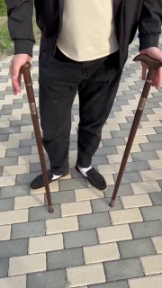 Человек держит две трости из венге с клинками: видны рукояти, длина трости около 90 см, сцена на тротуаре плиткой.