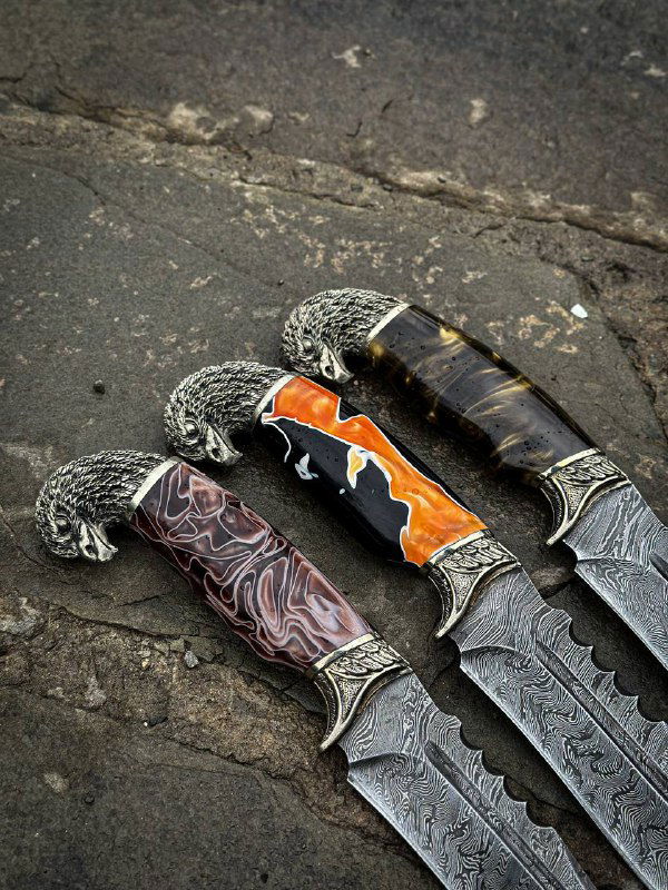 Крупный план трёх ножей «Орлан»: детали дамаска, текстура акриловых рукоятей и мельхиорное литьё на гарде заметны на тёмном фоне.