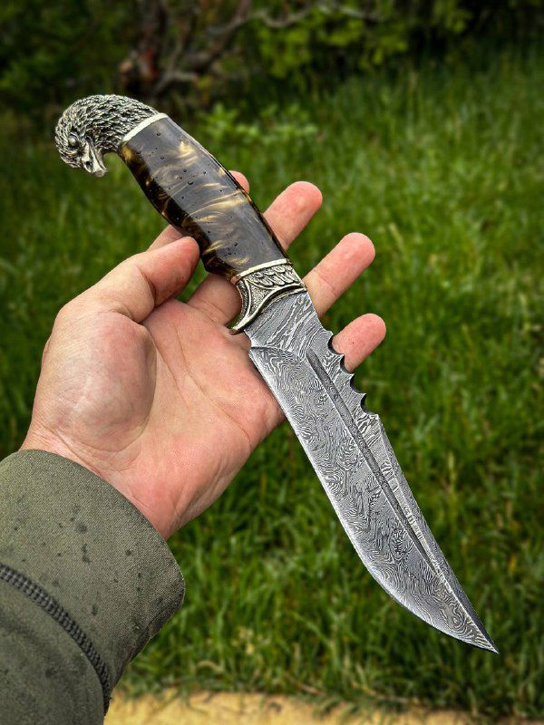 Нож «Орлан» в руке мастера: вид сбоку на дамасковый клинок и чёрно-жёлтую акриловую рукоять, показаны габариты и хват.