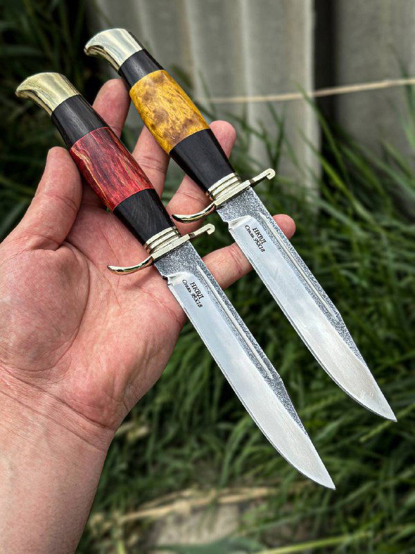 Крупный план двух финок НКВД в руке: стабилизированные рукояти красного и жёлтого оттенков, клинки 95х18 и мельхиоровые гарды видны отчётливо.