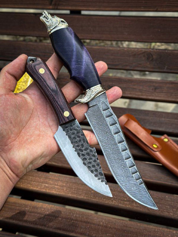 Две модели ножей в руке: компактный шкуродёр и основной нож «Волк» с дамасским клинком и декоративным мельхиоровым навершием.