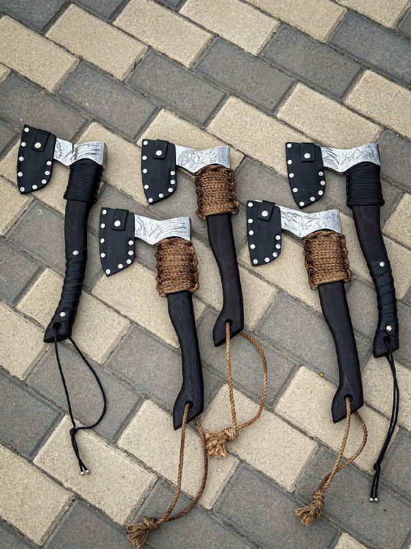 Групповая схема топоров в чехлах и без на плитке; видно металлические заклёпки чехлов, вариации плетения и отделки рукоятей из бука.