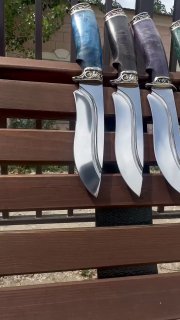 Крупный план ножей: видны профиль клинка, полировка, формы гарды и цветные рукояти из стабилизированной карельской берёзы для сравнения отделки.