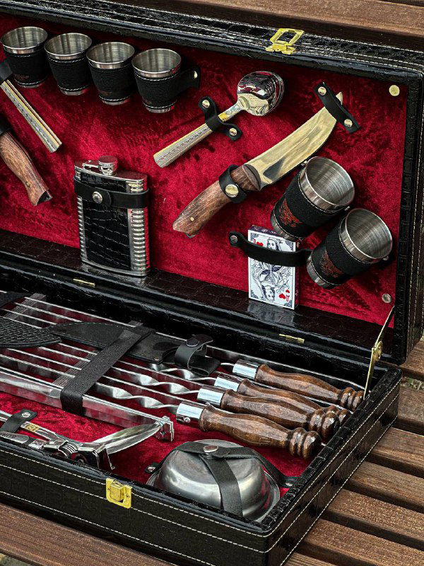 Вид внутри кейса: ножи, стаканы и дополнительные аксессуары для пикника и шашлыка, аккуратно размещённые в отделениях.