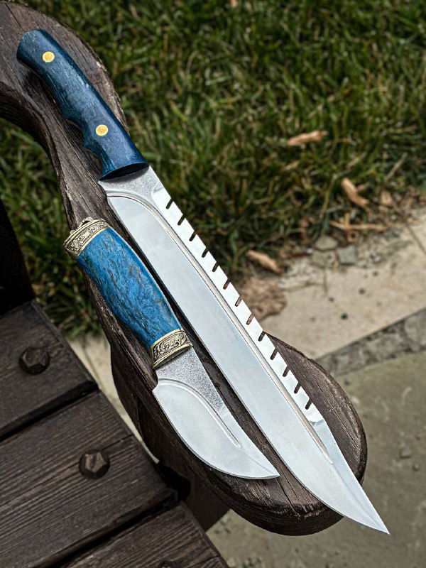 Крупный план цельнометаллического скотореза с синей стабилизированной рукоятью из карельской берёзы, крупно показывающий форму клинка и отделку обуха.