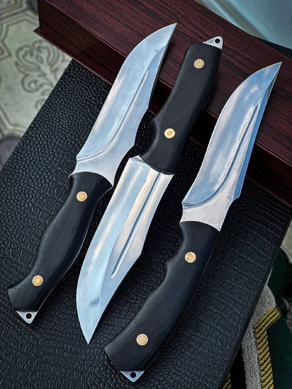 Три рабочих ножа разного профиля клинка, размещённые на тёмном фоне; видно отражения на лезвиях и детали рукояток из граба с латунными заклёпками.