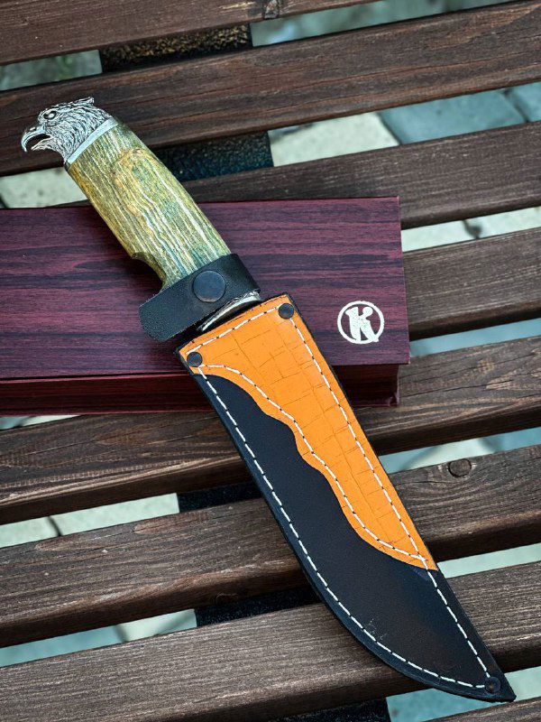 Кожаные ножны с оранжевой вставкой, рядом нож и деревянная коробка с логотипом мастерской — общий вид комплекта для хранения.